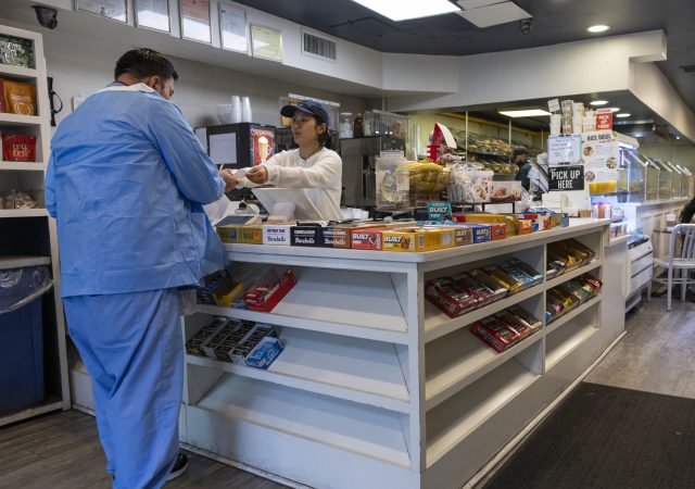 salario-minimo-connecticut-trabajador Trabajadora entregando un recibo en un comercio, imagen representativa de trabajadores por hora